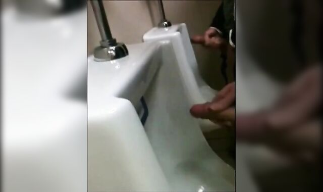 two slim dicks getting wanked at the urinals
