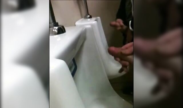 two slim dicks getting wanked at the urinals